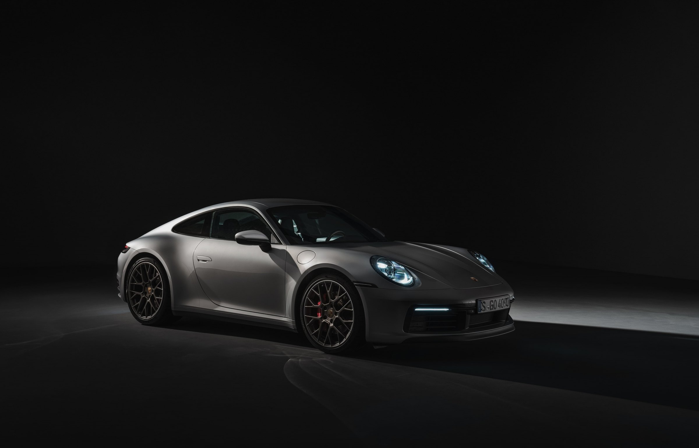 Porsche 911 plateado en un estudio oscuro con los faros encendidos — plantilla VELOCITY MOTORS